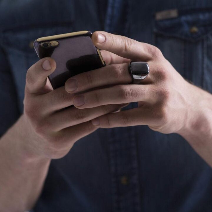 Person holding a phone with Oura Wellness ring in hand