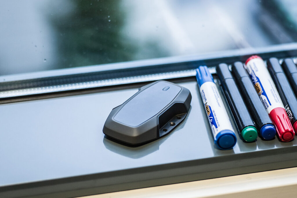 Thingsee One IoT device in a windowsill next to pens 