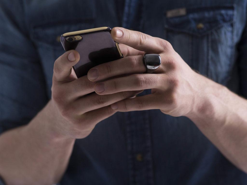 Person holding a phone with Oura Wellness ring in hand