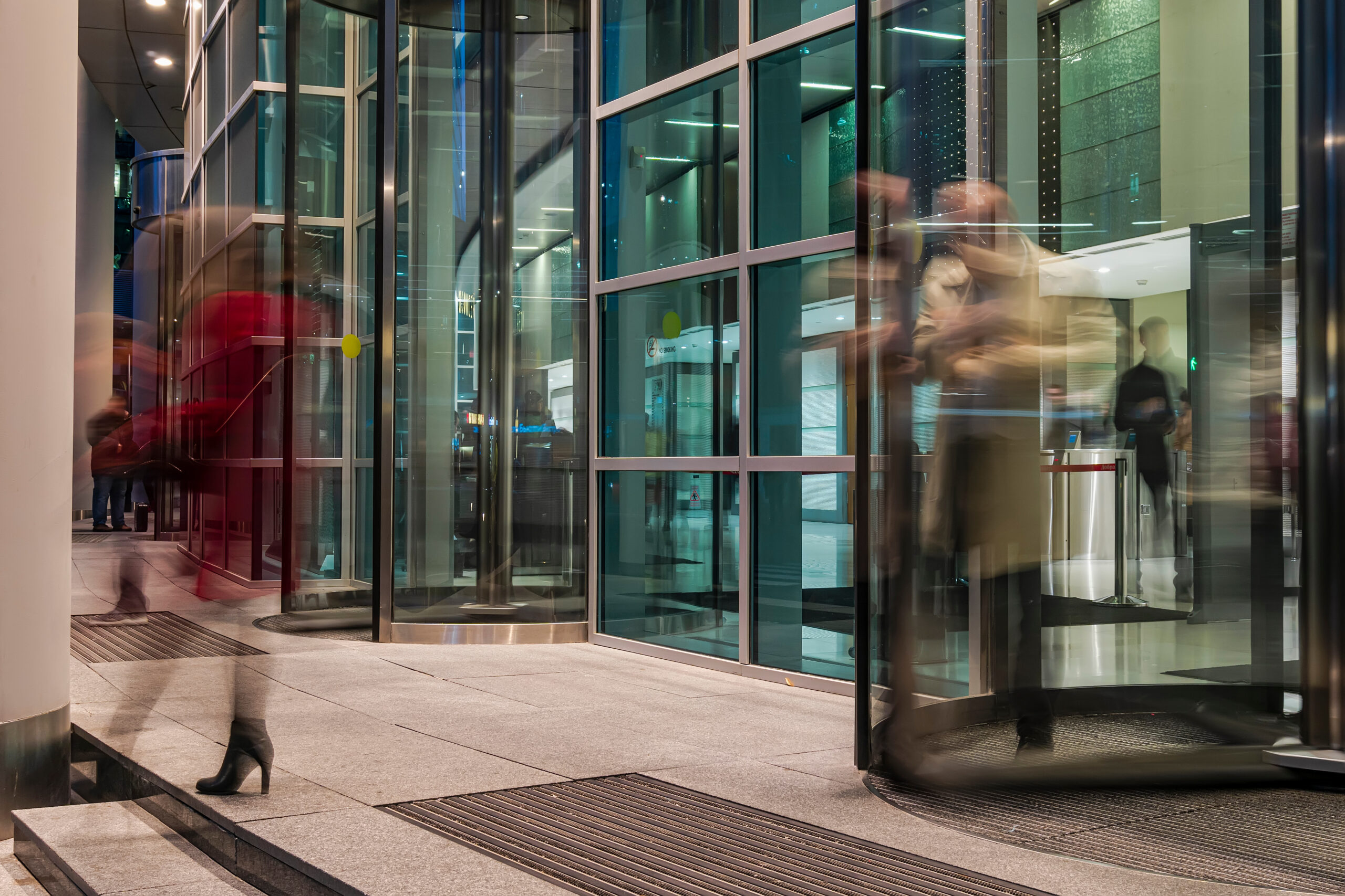The flow of people passing through the rotating door of the modern office building