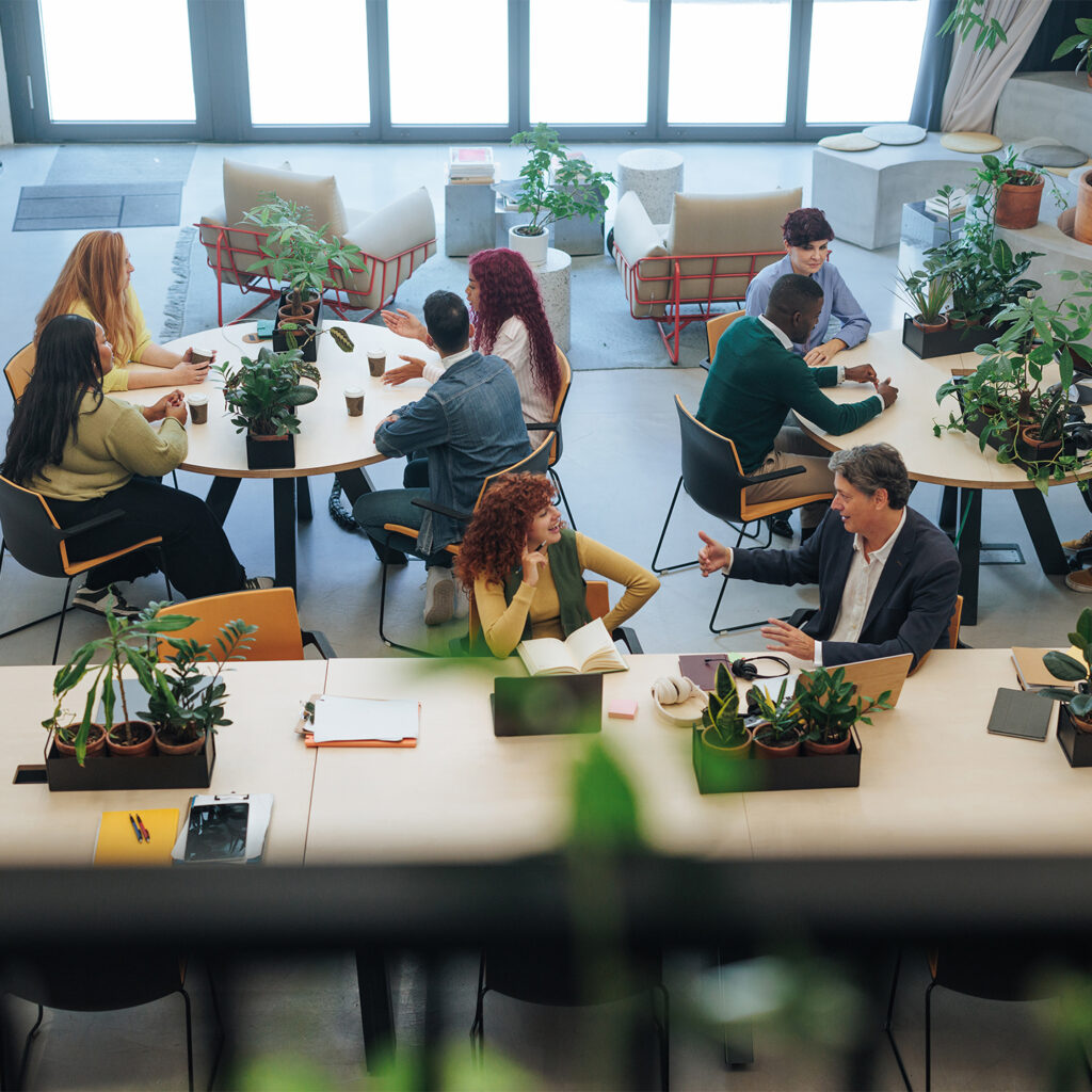 High angle view of businesspeople working and collaborating in a modern, plant-filled office space, fostering a productive and eco-conscious work environment