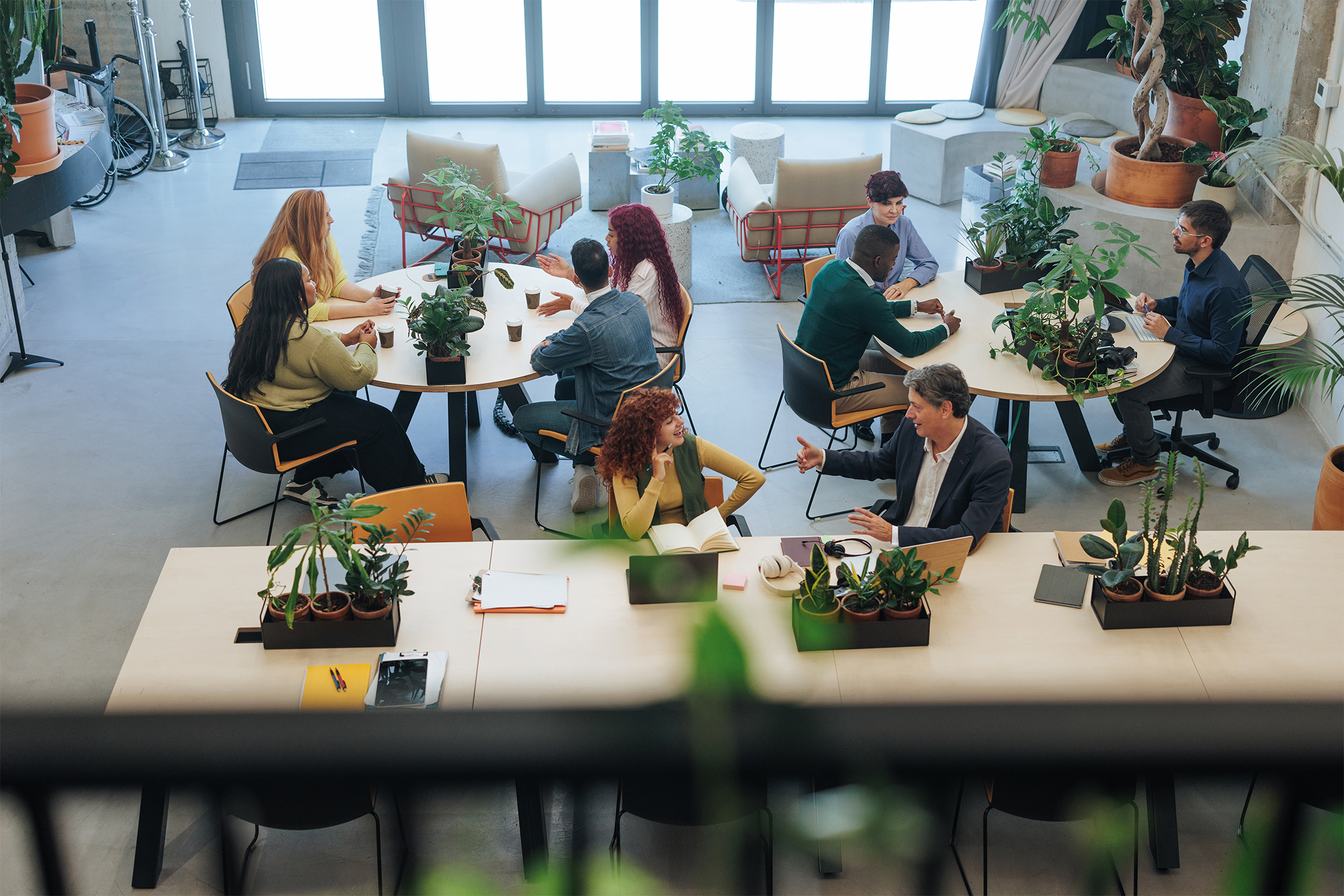 High angle view of businesspeople working and collaborating in a modern, plant-filled office space, fostering a productive and eco-conscious work environment