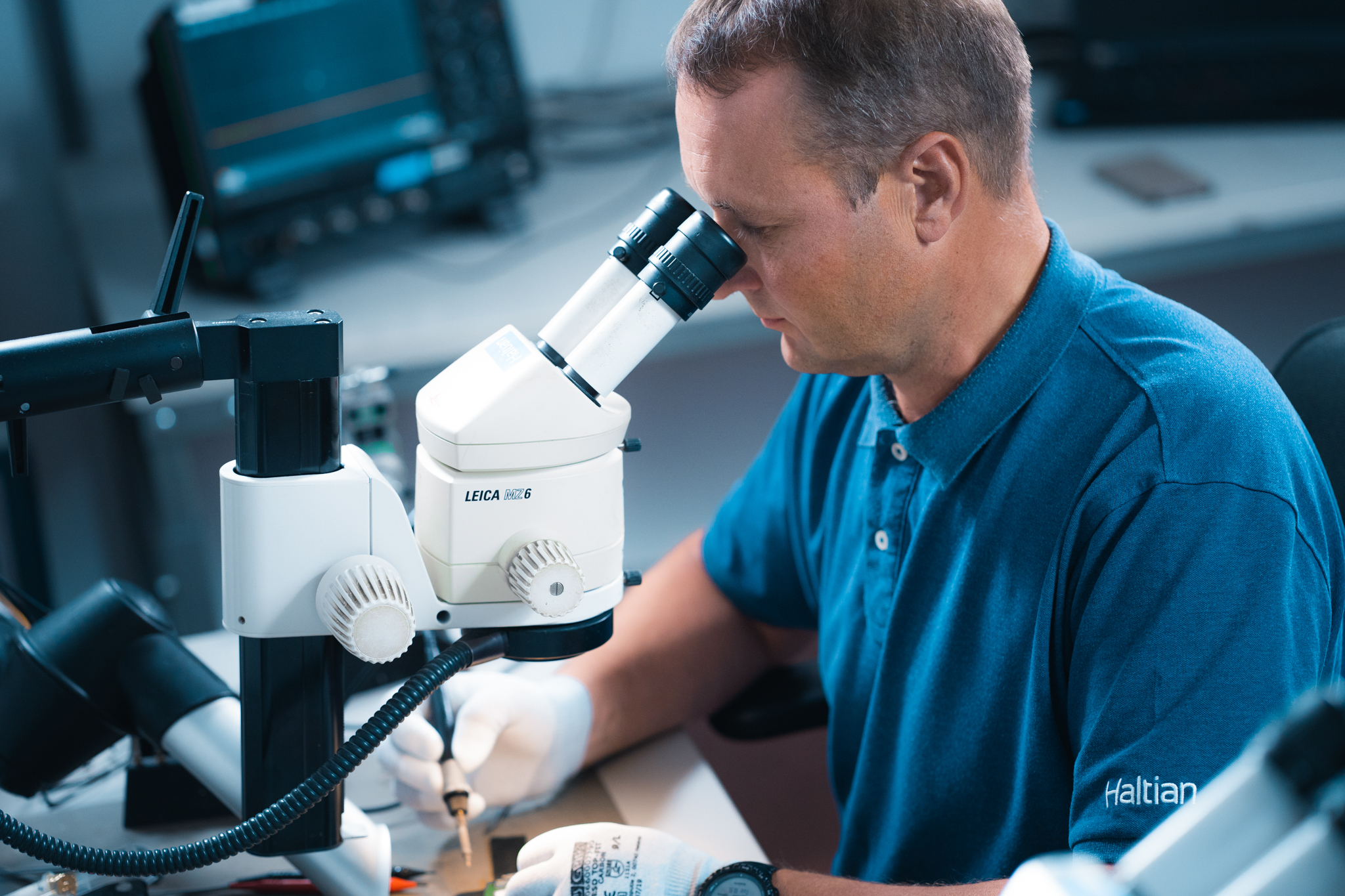 Haltian engineer doing sustaining engineering and maintenance work on a circuit board under a microscope